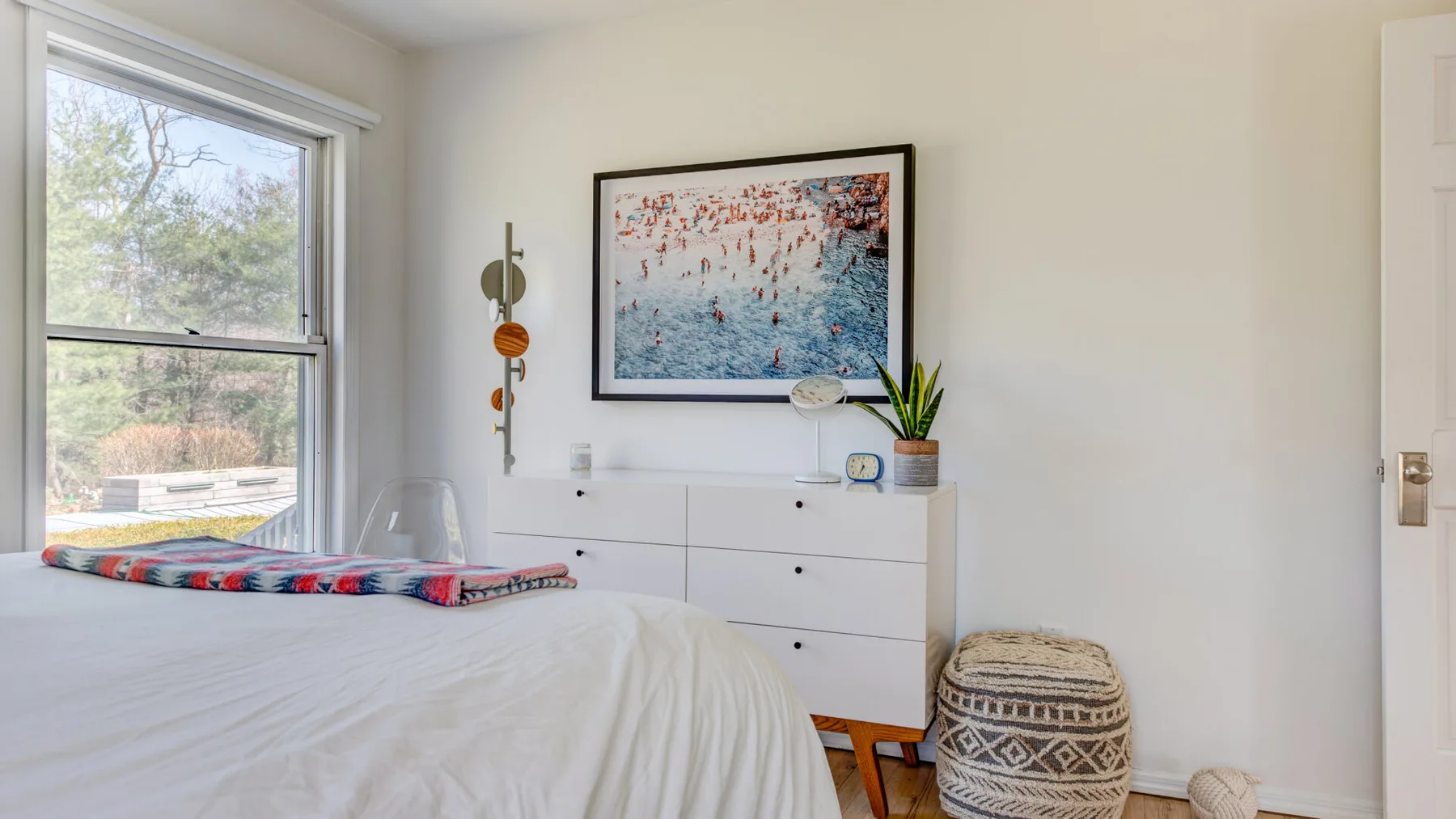 Un dormitorio con una cama, una cómoda y una obra enmarcada en la pared.