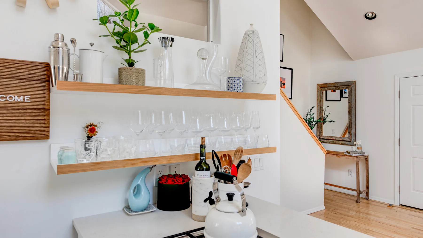 Una cocina luminosa con estantes abiertos que exhiben cristalería y pequeños objetos decorativos.