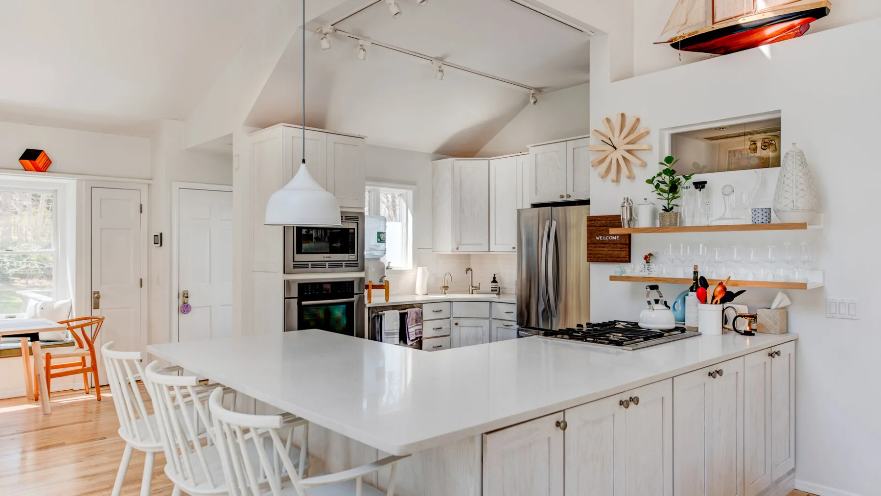 Una cocina luminosa con gabinetes blancos, una isla grande y asientos de comedor.