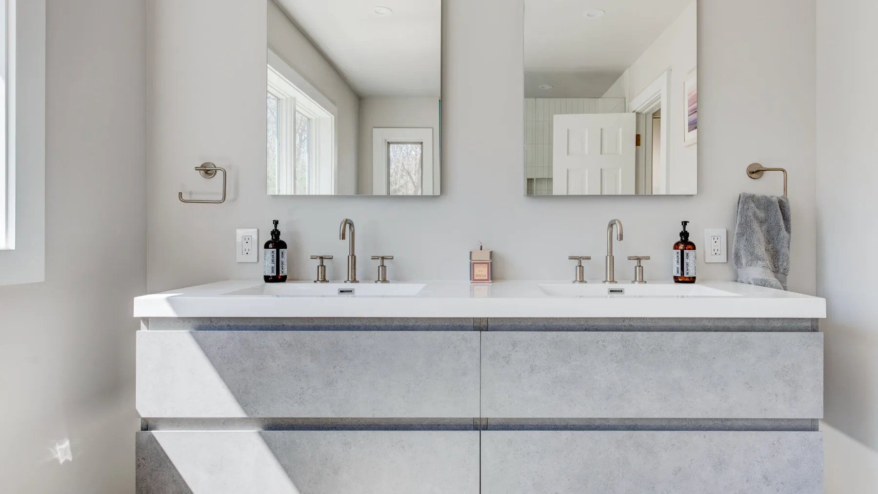 Un tocador de baño luminoso con dos lavabos, espejos y grifos.