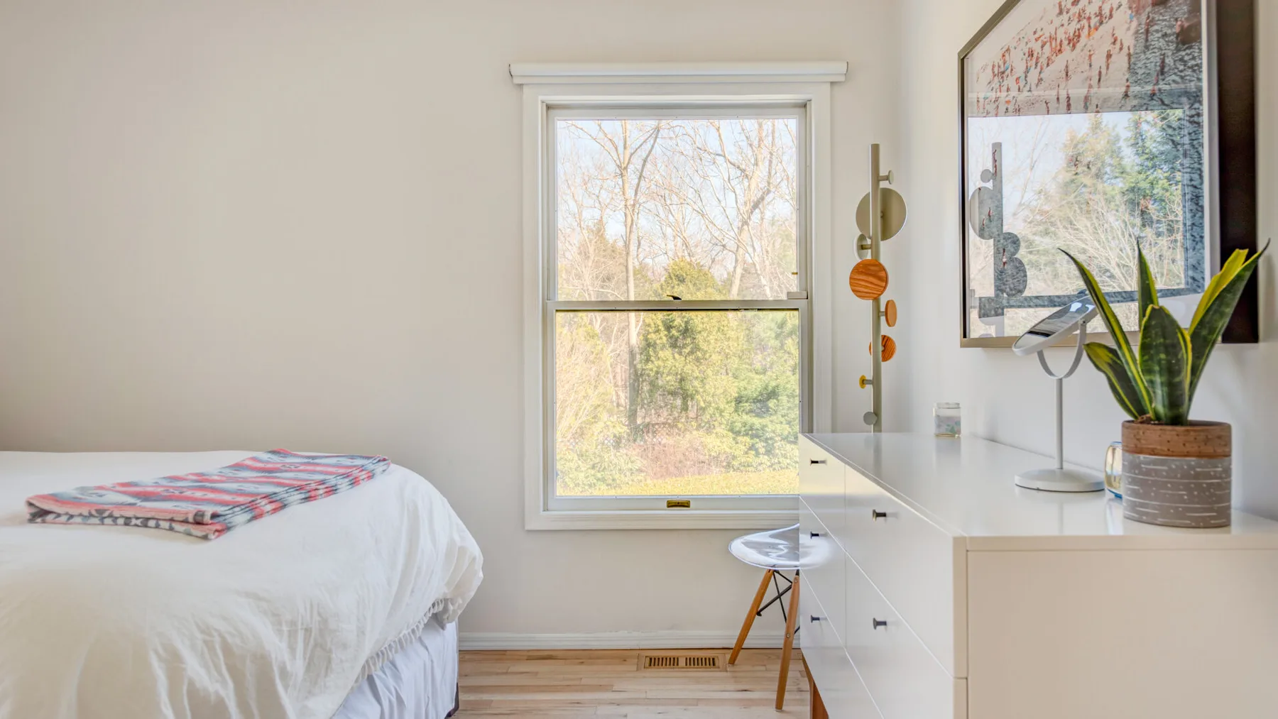 Un dormitorio con una cama junto a una ventana y un escritorio blanco.