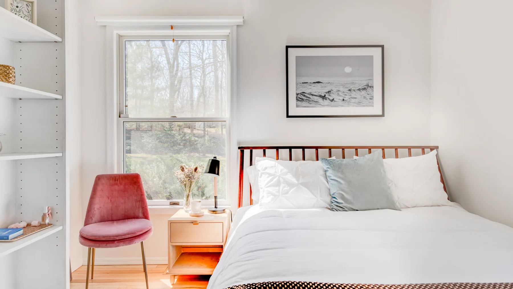 Un dormitorio luminoso con una cama tendida junto a una ventana.