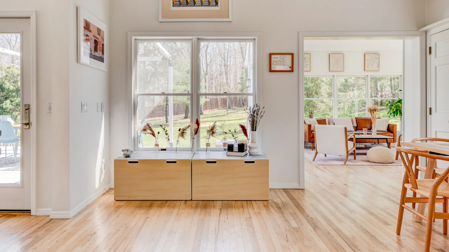 Un comedor luminoso se abre a una sala de estar, con un mueble bajo bajo la ventana.