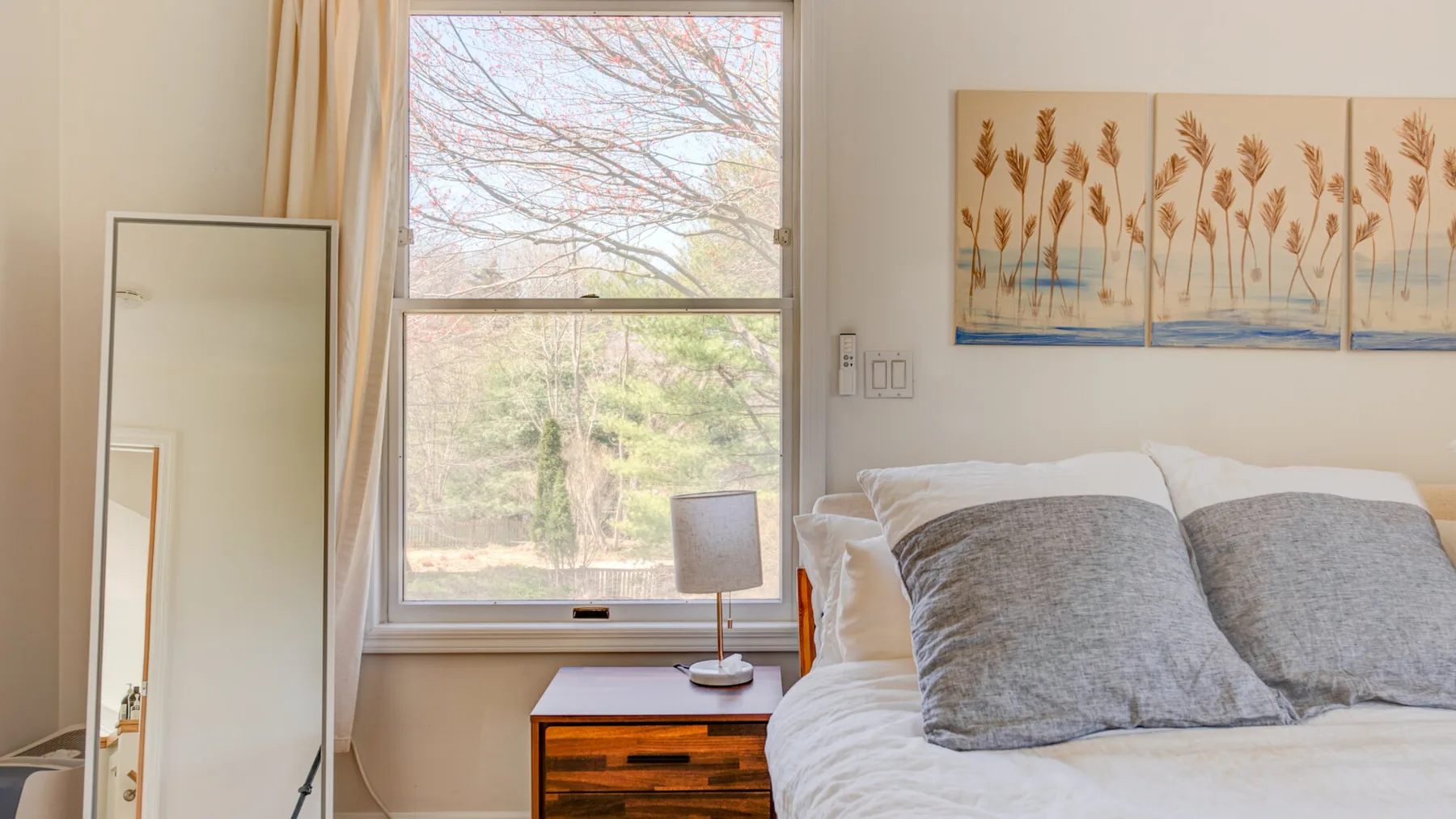 Un dormitorio con una cama junto a una ventana y una mesita de madera.