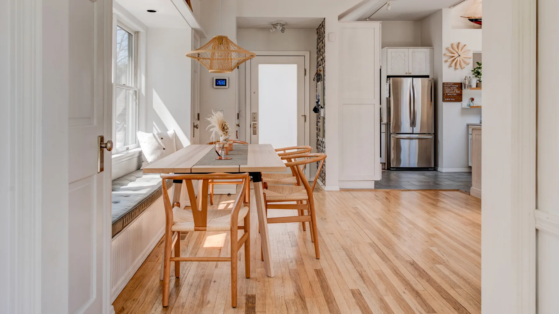Un comedor luminoso con una mesa de madera y sillas junto a grandes ventanas.
