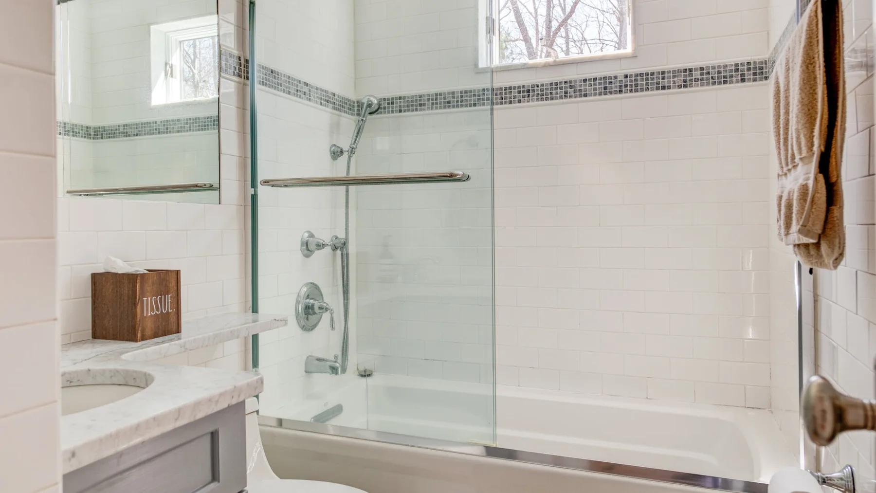 Un baño alicatado con bañera, mampara de vidrio y lavabo.