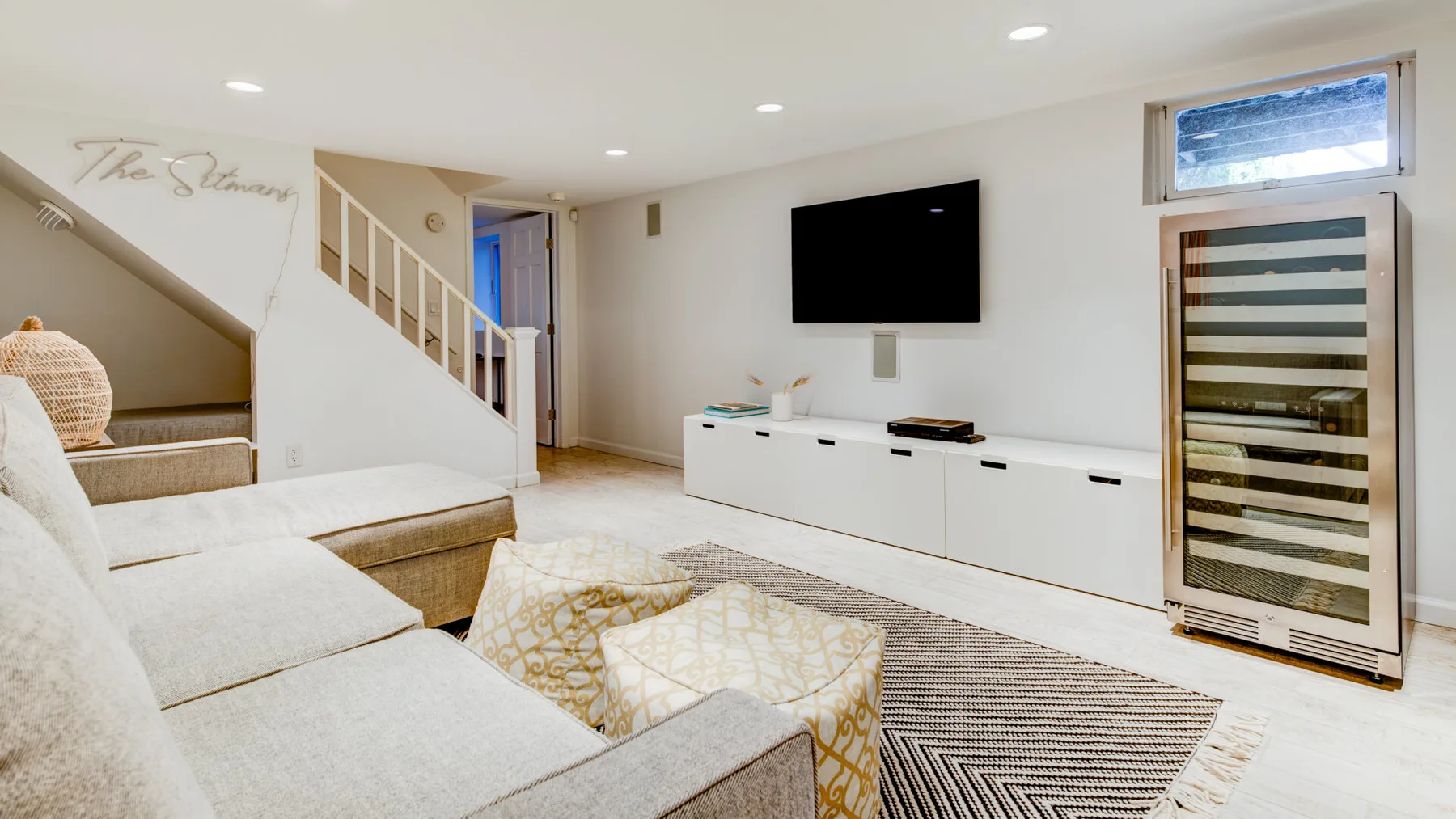 Una sala de estar luminosa con asientos, un televisor y un mueble bajo.