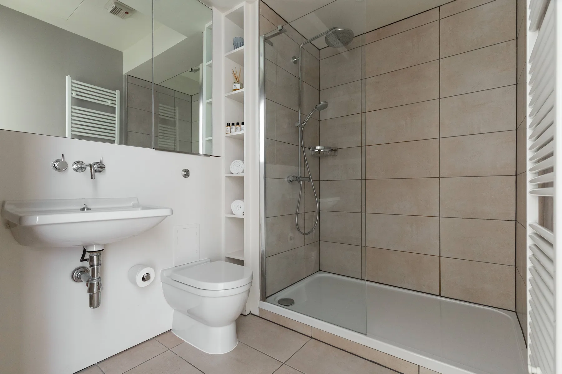 Un baño moderno con lavabo, inodoro y ducha con mampara de vidrio.