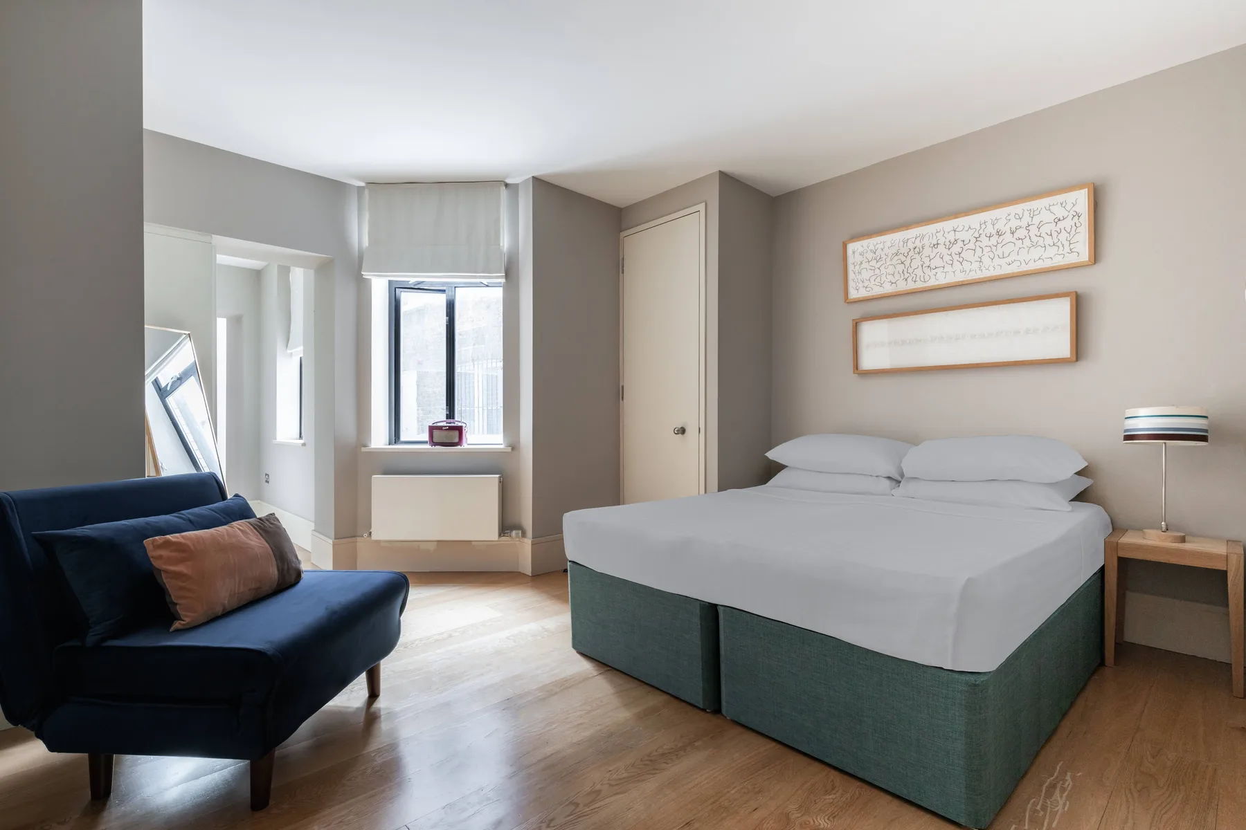 Un dormitorio con una cama doble, un sofá oscuro y una ventana.
