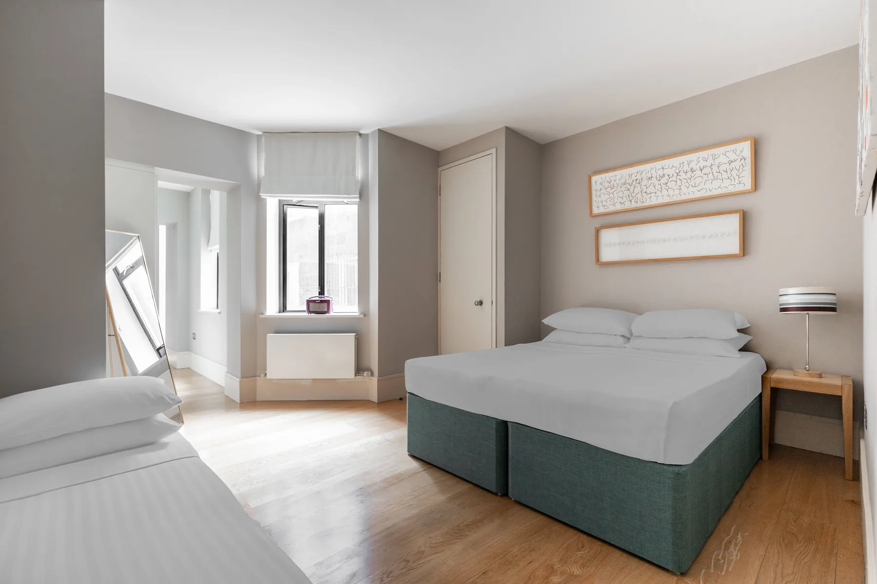 Un dormitorio con camas, una ventana y cuadros en la pared.