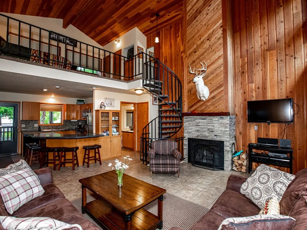 Una sala con paredes de madera, chimenea de piedra y escalera de caracol.