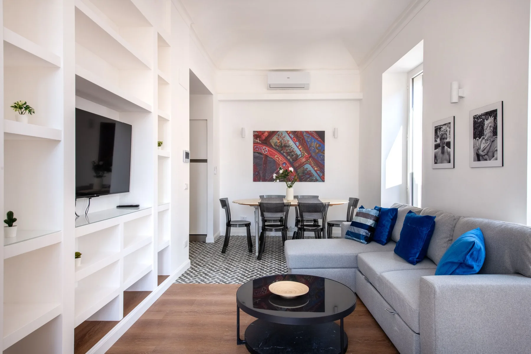 A bright living and dining room with built-in shelving and a sectional seating area.
