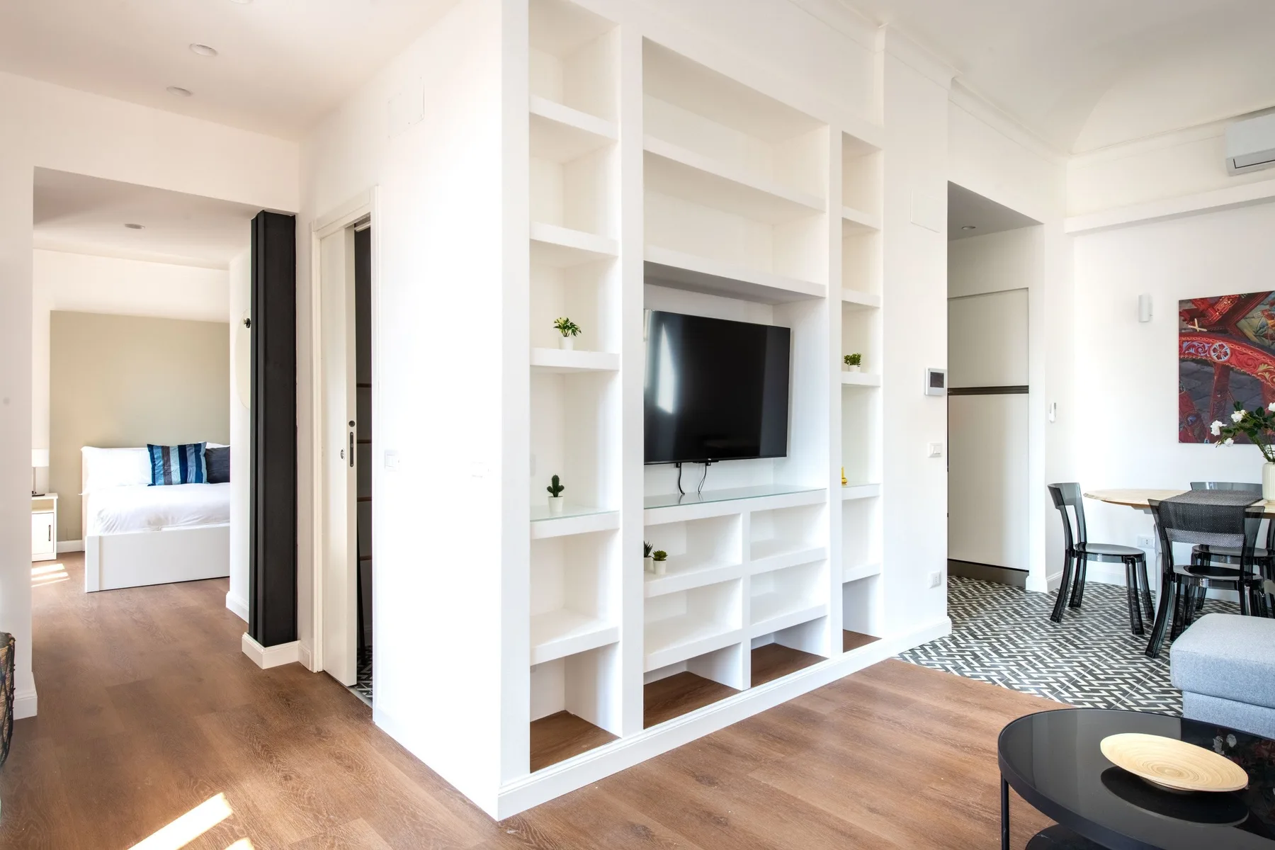 A bright living area with built-in shelving, a television, and an adjoining dining space.