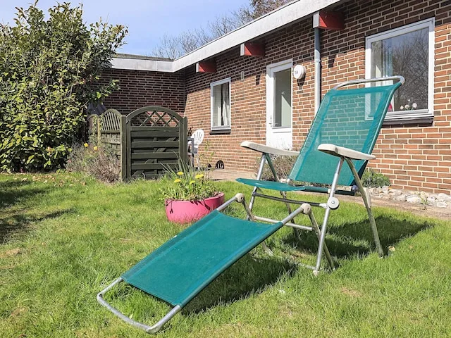A grassy outdoor patio beside a brick building, with reclining seating.