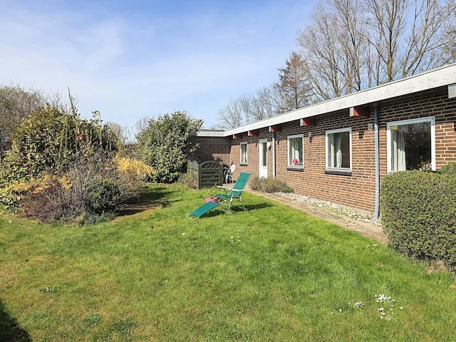 A brick house borders a grassy yard with outdoor seating.