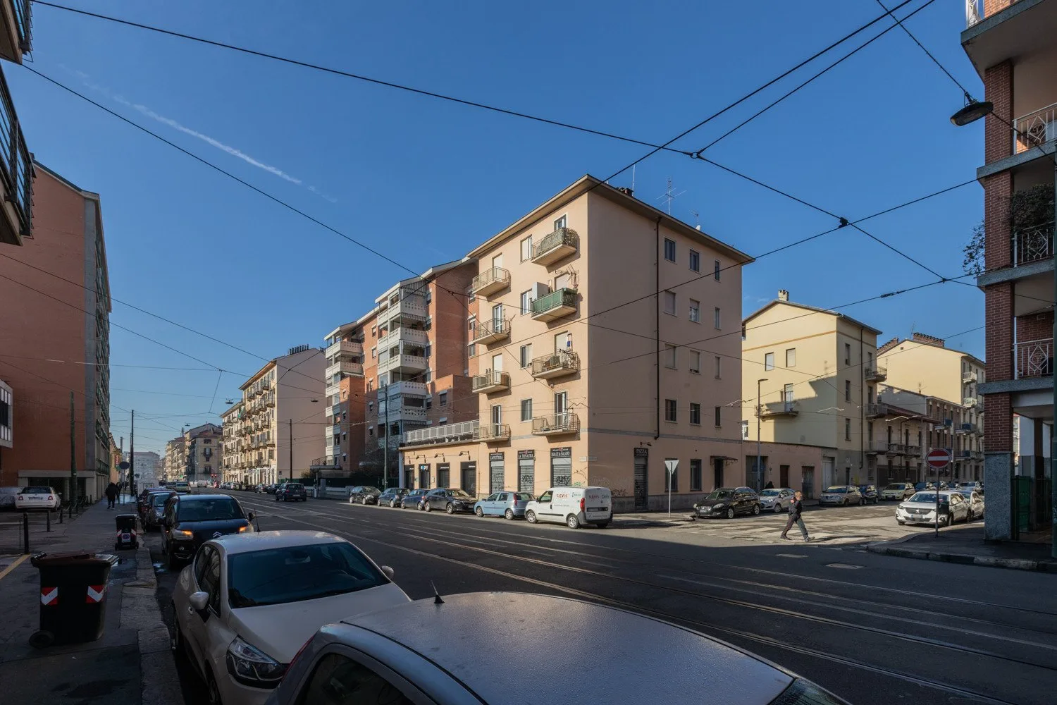 Una calle urbana bordeada de edificios de apartamentos y coches estacionados.