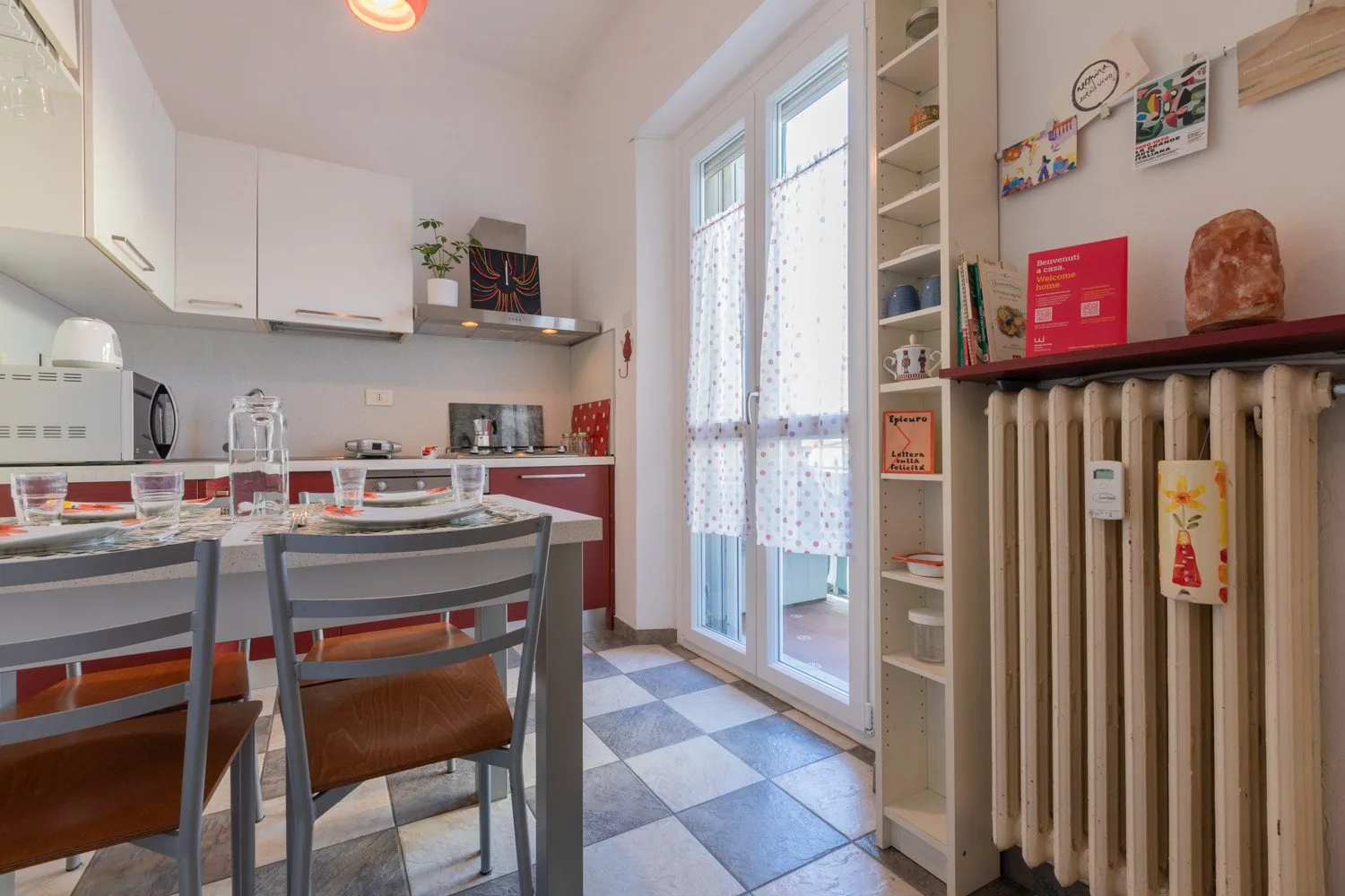 Una cocina luminosa con una mesa de comedor y puertas de vidrio que dan a un pequeño balcón.