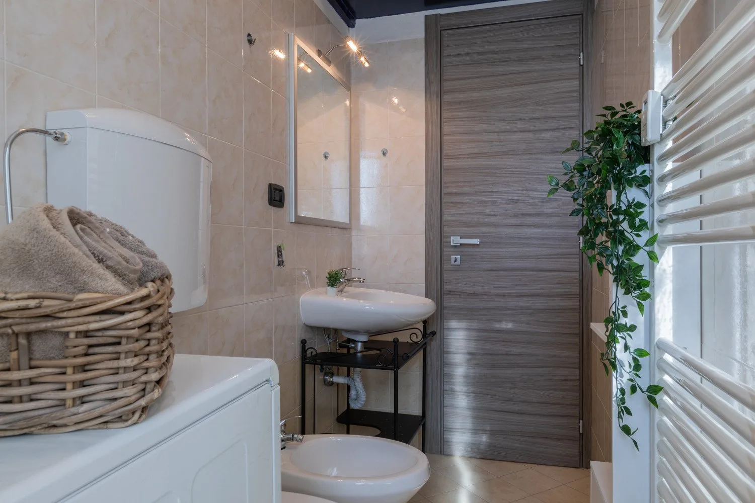 Un baño alicatado con lavabo, inodoro y una puerta de madera.