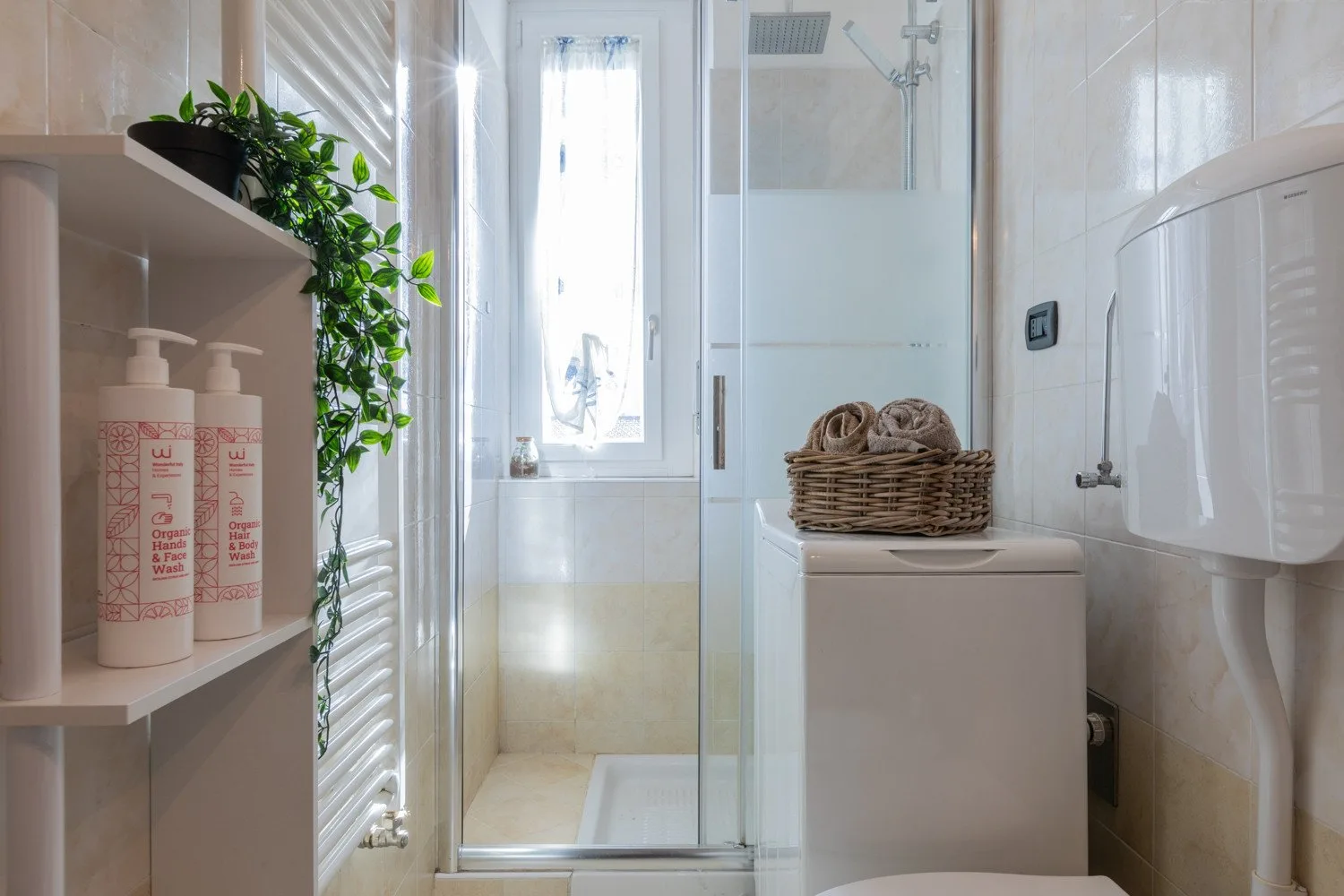 Un baño luminoso con una ducha de vidrio y una ventana pequeña.