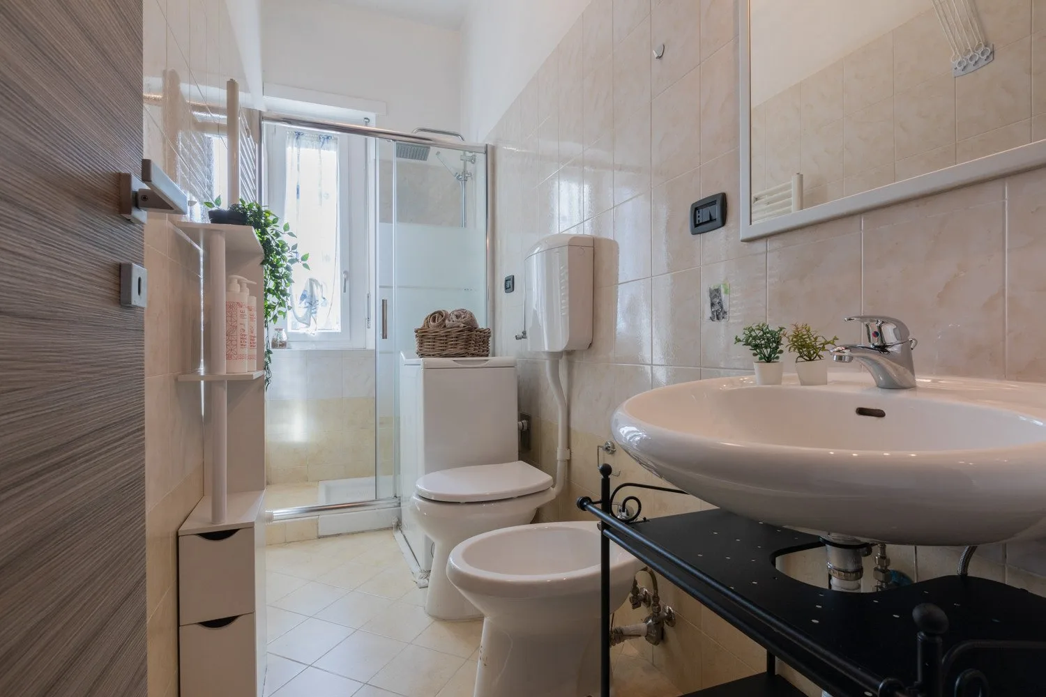 Un baño luminoso con ducha de vidrio, inodoro y lavabo.