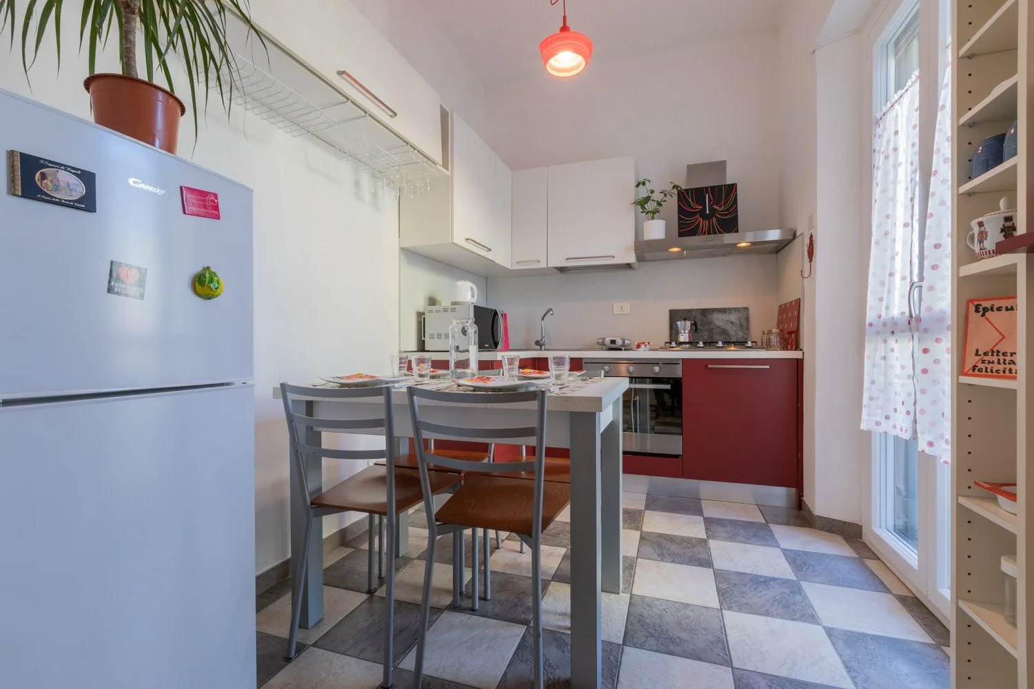 Una cocina compacta con mesa y sillas junto a una ventana luminosa.
