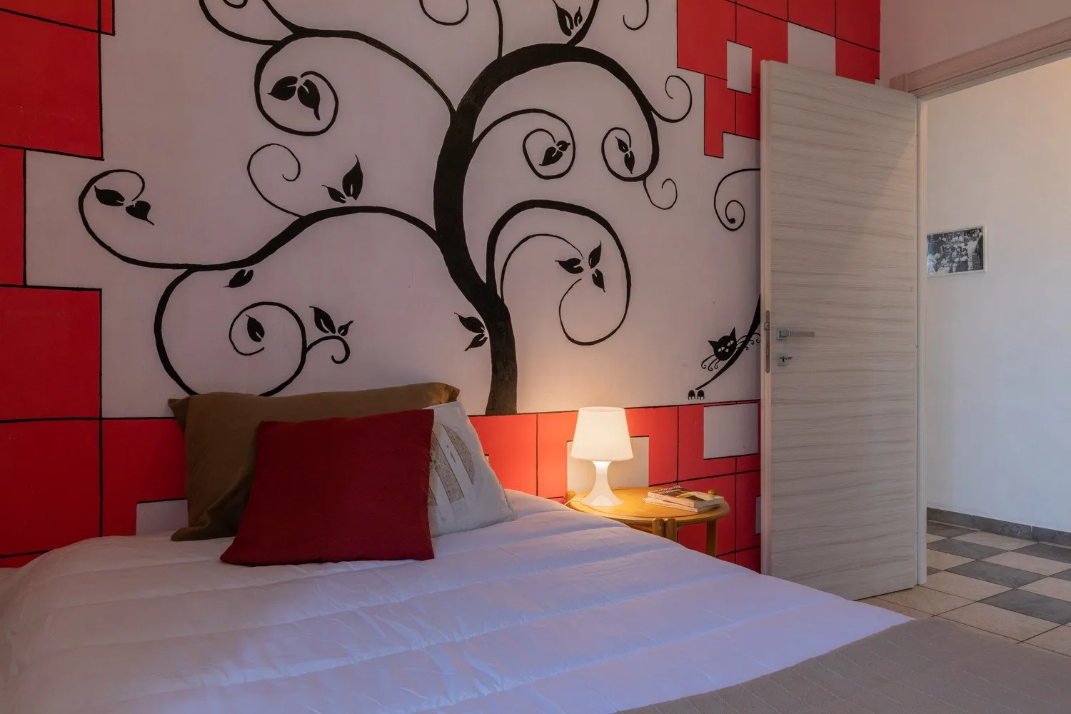 Un dormitorio con una cama bajo un gran mural en blanco y negro y paneles rojos.