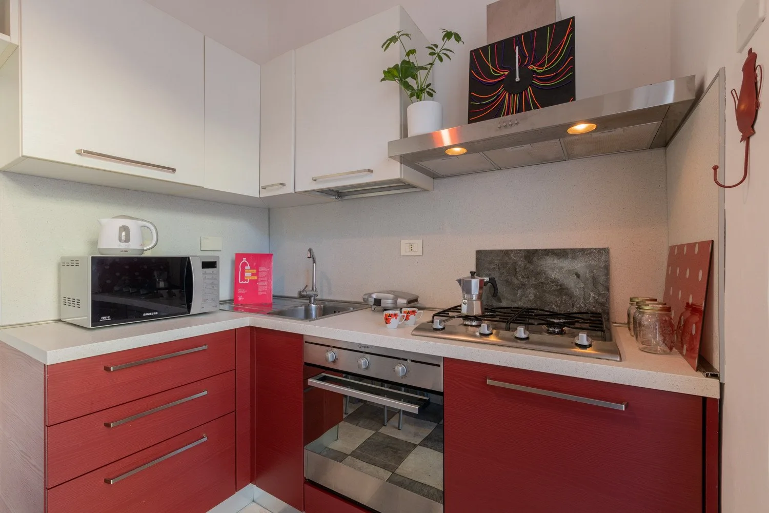 Una cocina compacta con gabinetes rojos, una encimera y una estufa.
