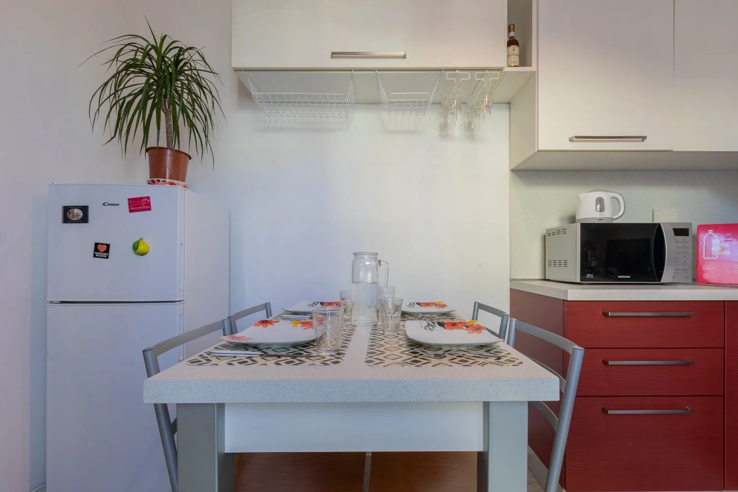 Una mesa de comedor está puesta en una cocina compacta con armarios y electrodomésticos.