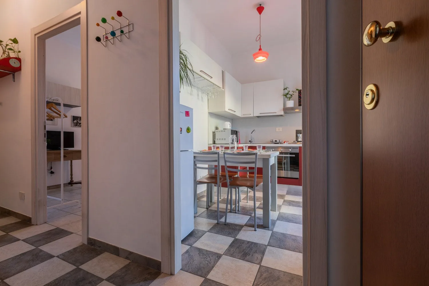 Se ve una cocina con una mesa y taburetes a través de la puerta.