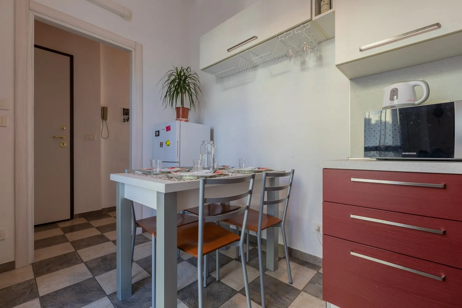 Una cocina compacta con mesa de comedor, sillas y armarios rojos.