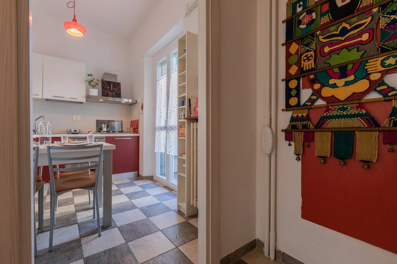 Una cocina luminosa con una mesa de comedor y un tapiz colorido.