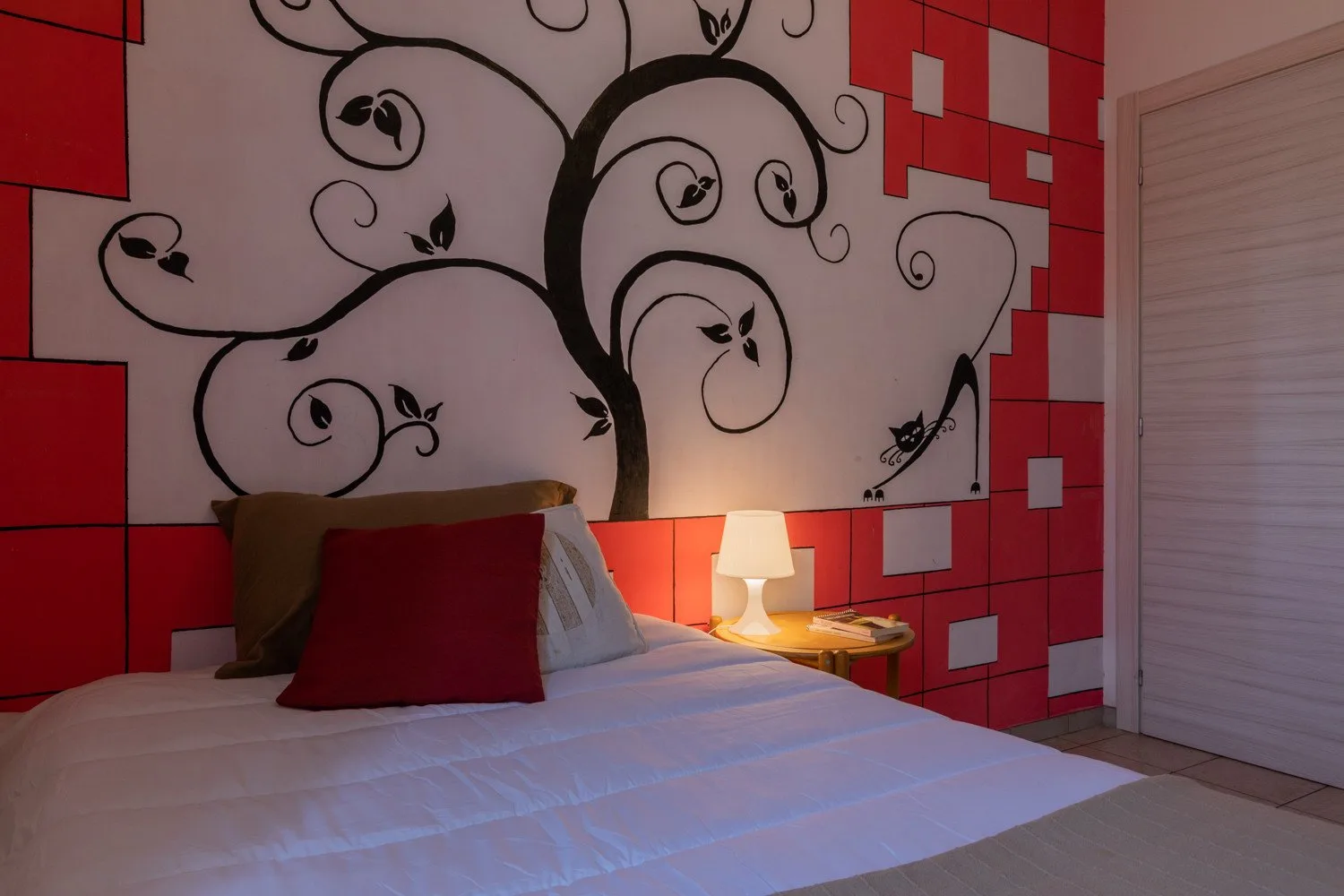 Un dormitorio con una cama bajo un gran mural en blanco y negro y paneles rojos.