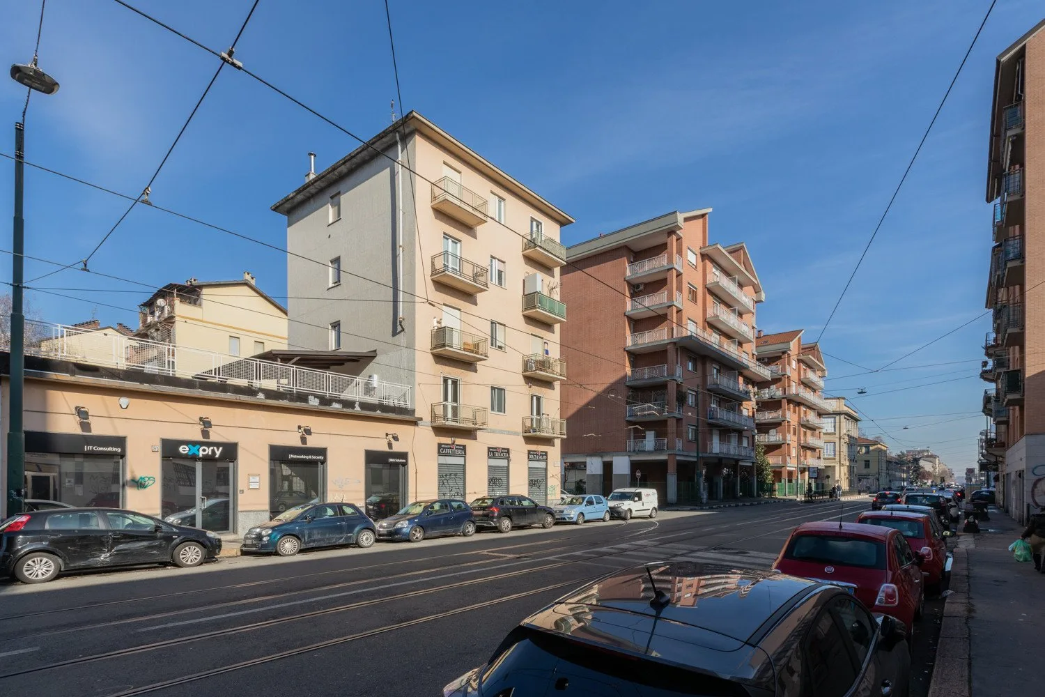 Una calle urbana bordeada de edificios de apartamentos y coches estacionados.