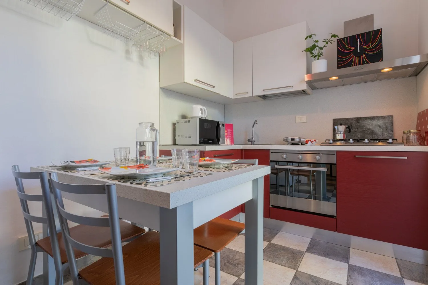 Una cocina con zona de comedor y una mesa junto a los armarios rojos.