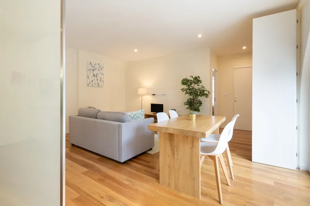 A bright living and dining area with a wooden table and seating.
