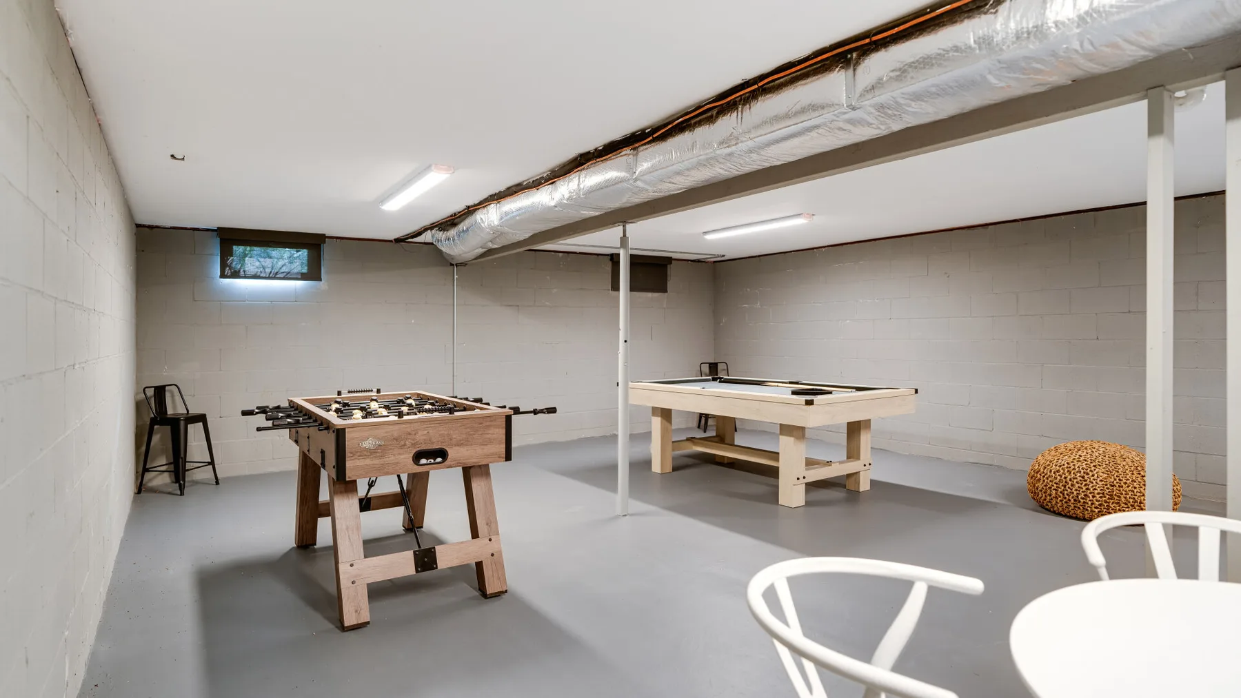Una sala recreativa en el sótano con futbolín, mesa de billar y asientos.