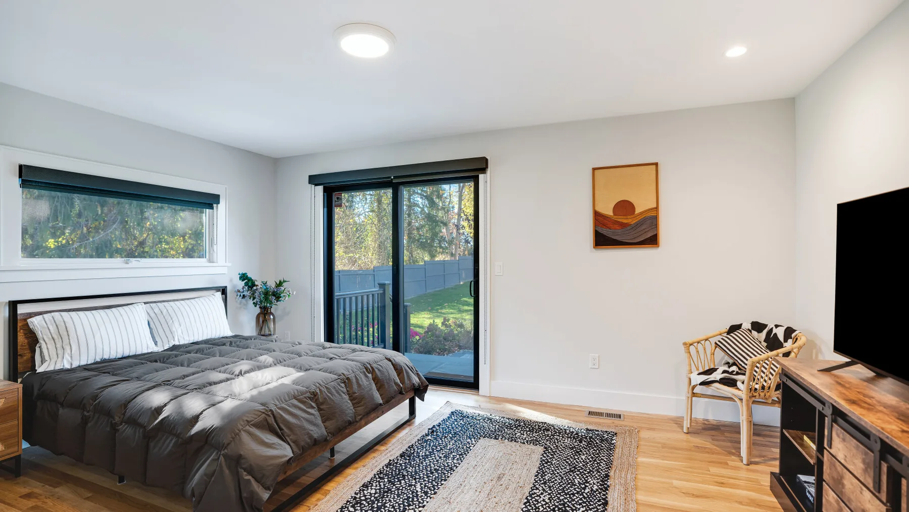 A bedroom with a bed, sliding glass doors, and a seating area.