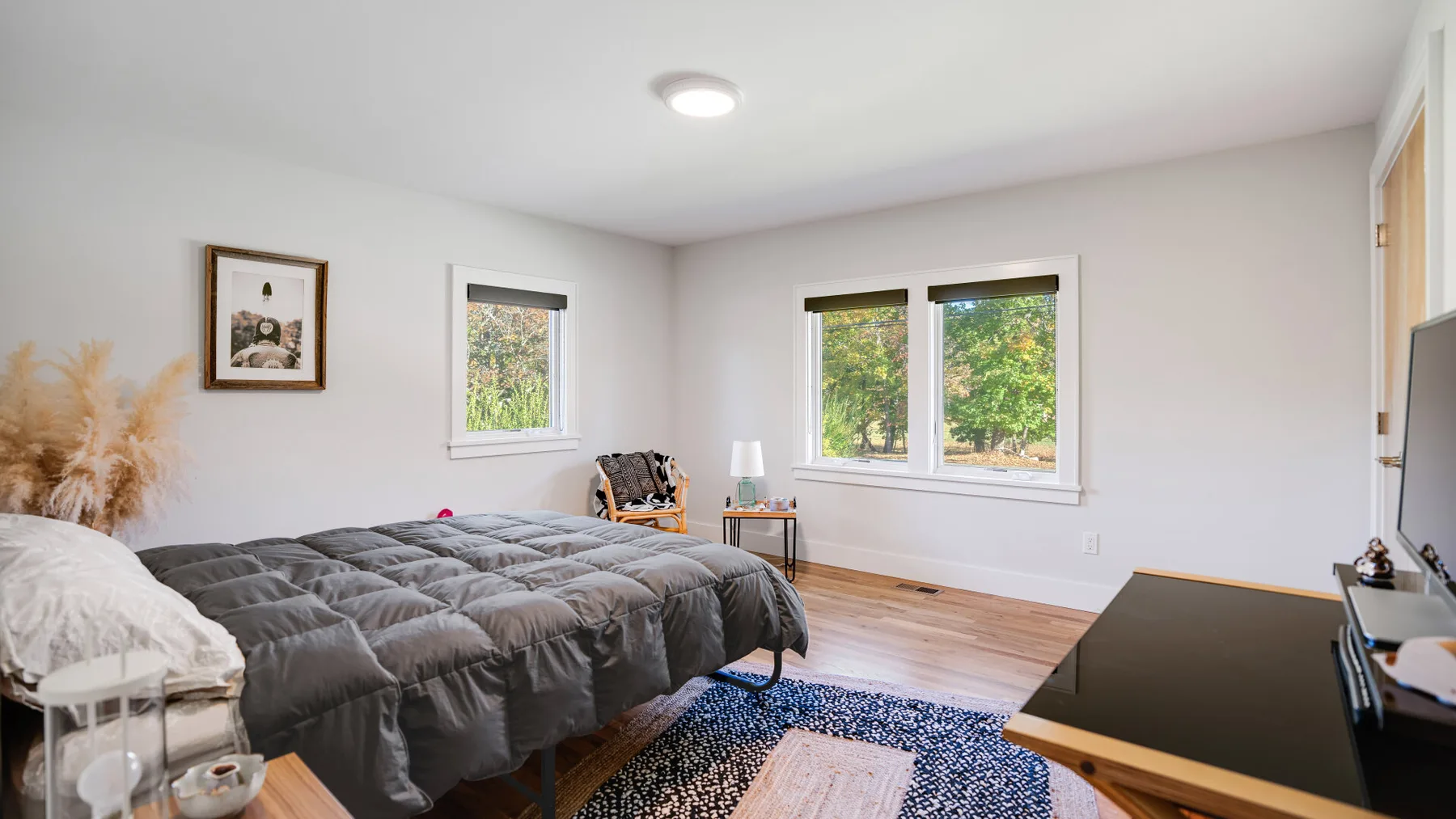 Un dormitorio luminoso con una cama, ventanas y un escritorio.
