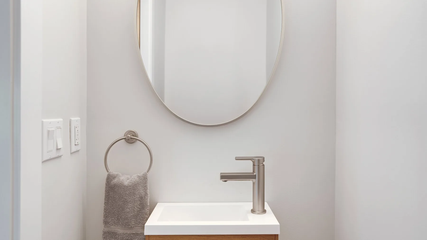 A bathroom vanity with a vessel sink, faucet, and oval mirror.