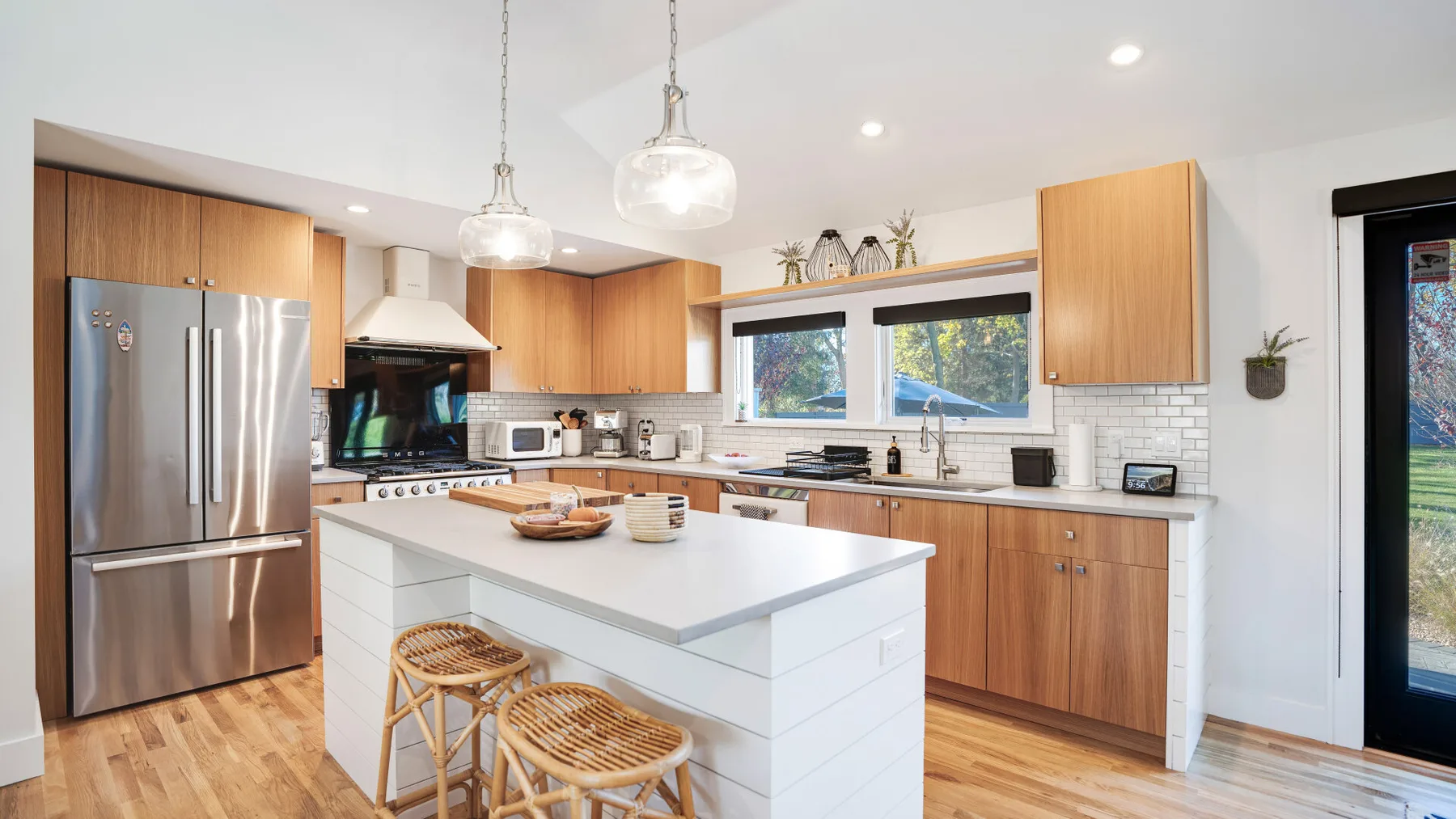 Una cocina luminosa con una isla central, gabinetes de madera y electrodomésticos de acero inoxidable.