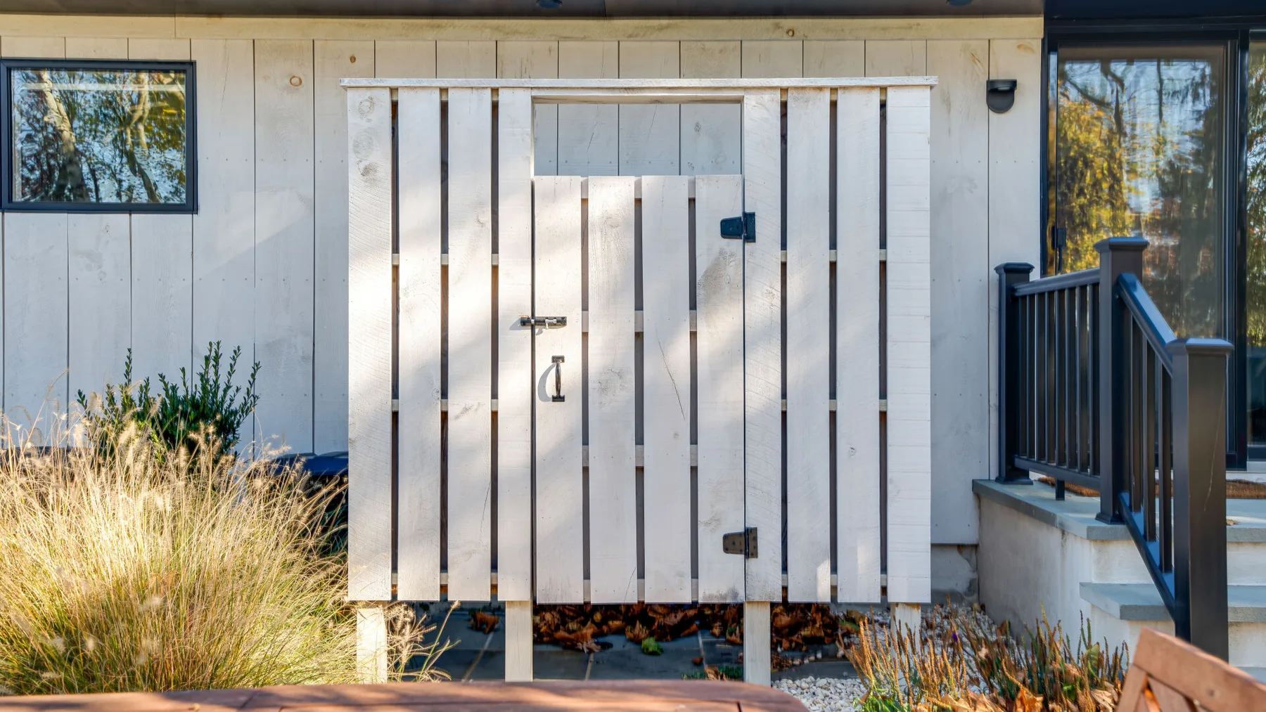 A small outdoor shower enclosure stands beside a dark-railed walkway.
