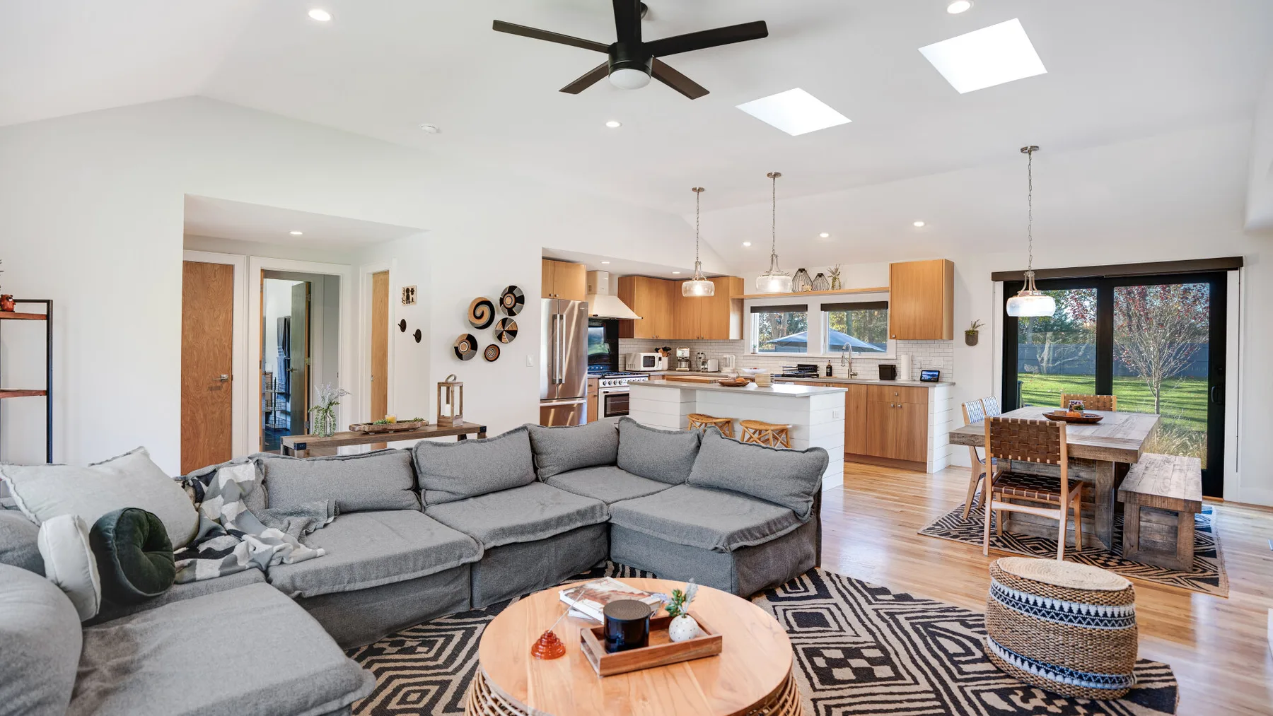 An open-plan living room and kitchen with a large sectional seating area and dining table.