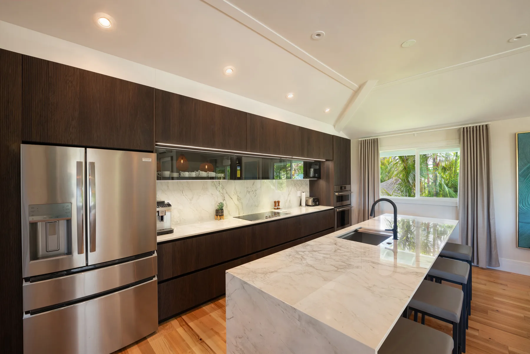 Una cocina moderna con gabinetes oscuros, electrodomésticos de acero inoxidable y una isla grande.
