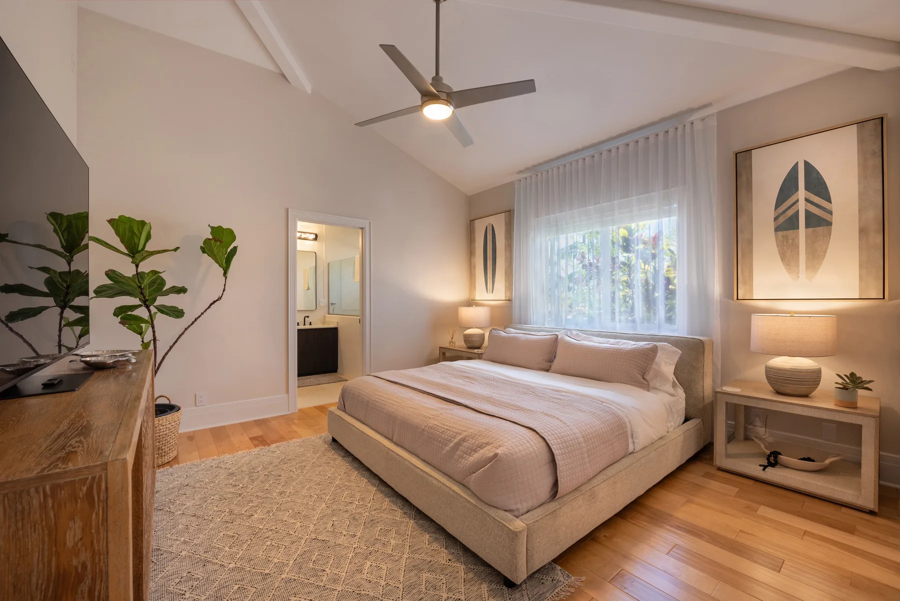 Un dormitorio con una cama grande, mesitas de noche y una ventana con cortinas translúcidas.