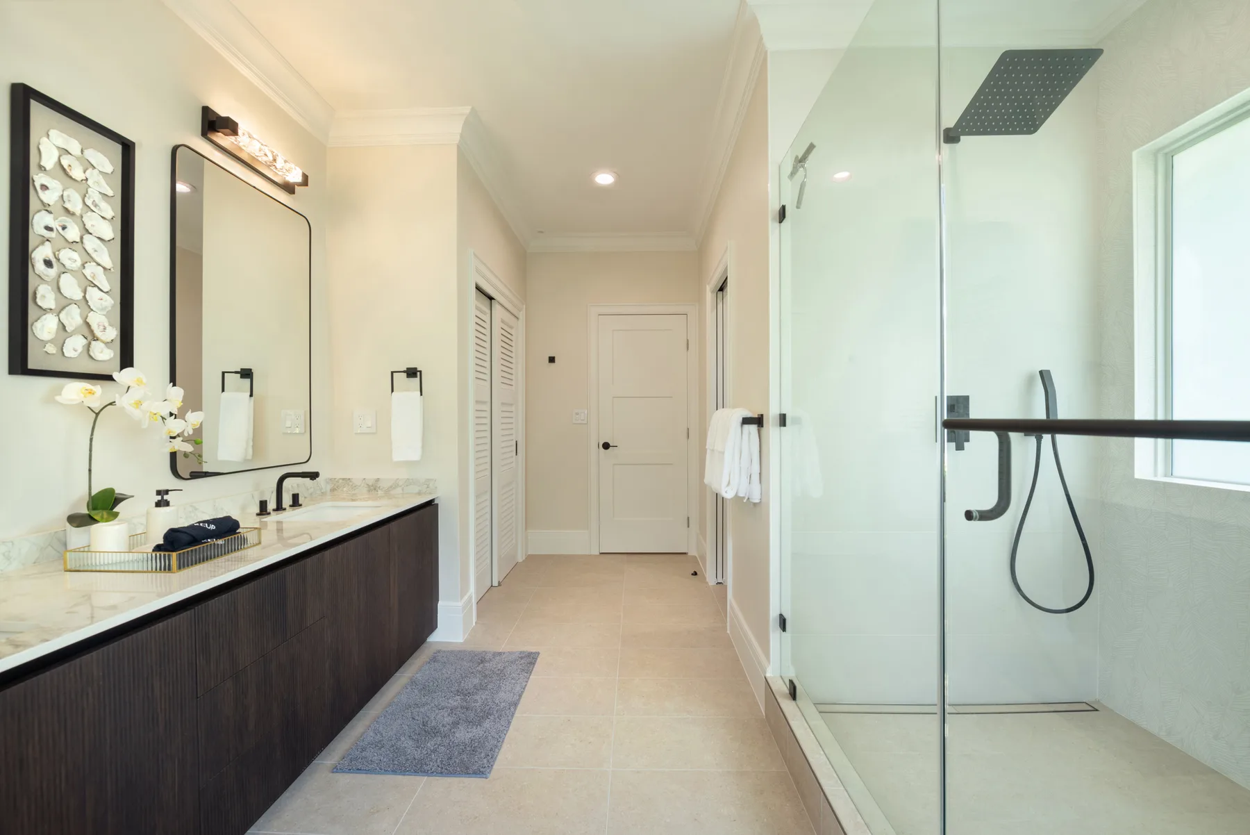 Un baño luminoso con un lavabo largo y una ducha con mampara de vidrio.