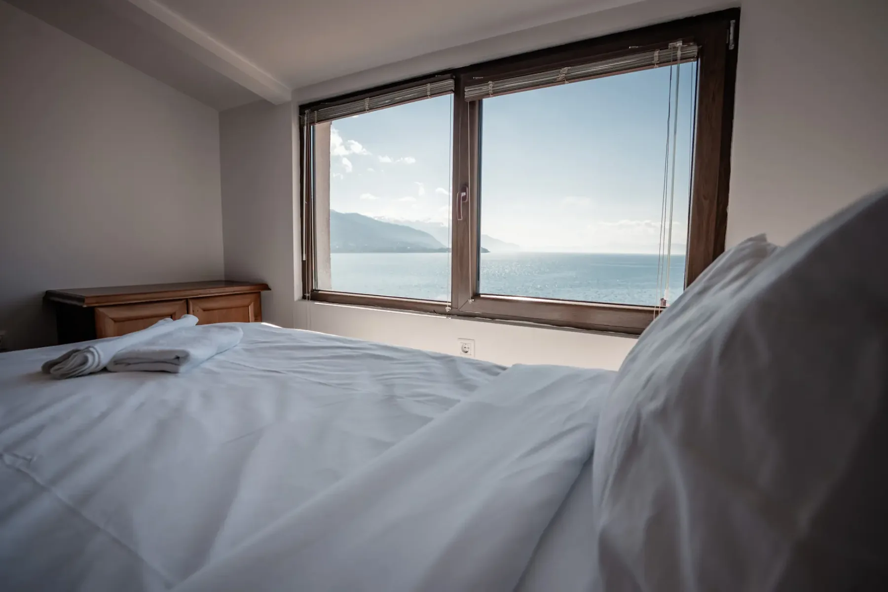 Cama del ático orientada hacia una ventana con vistas al lago y a las montañas