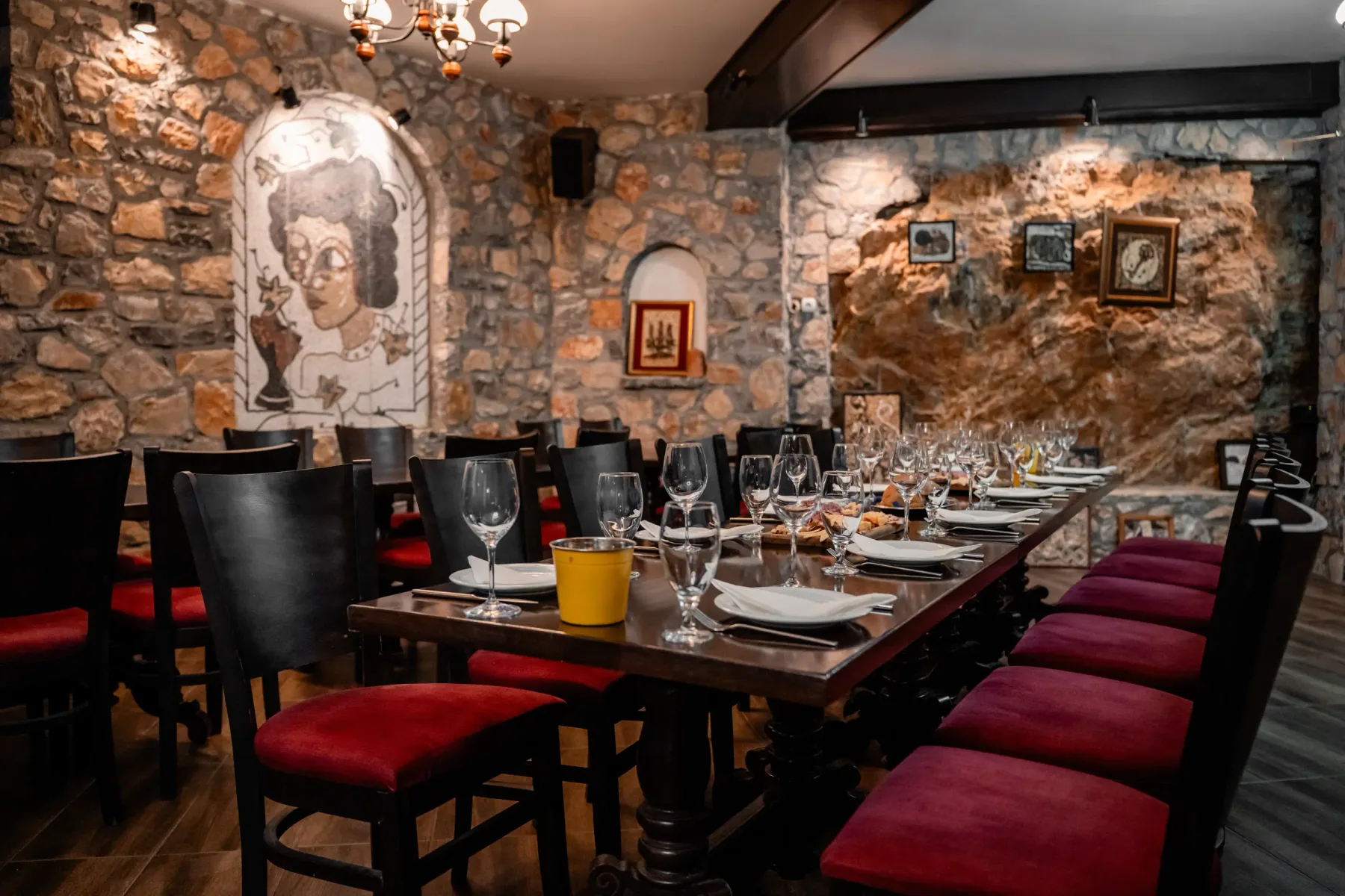 Bar de vinos de piedra con una mesa larga bajo mosaicos de guijarros