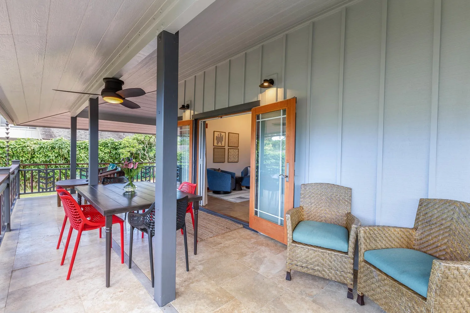 A covered patio with wicker seating and an open doorway into the room.