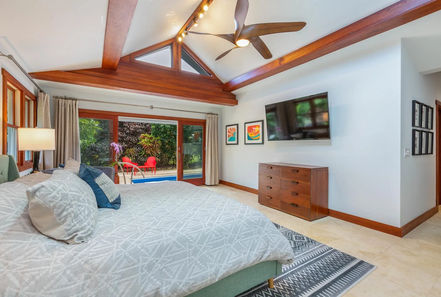 A bedroom with a large bed facing glass doors and a garden.