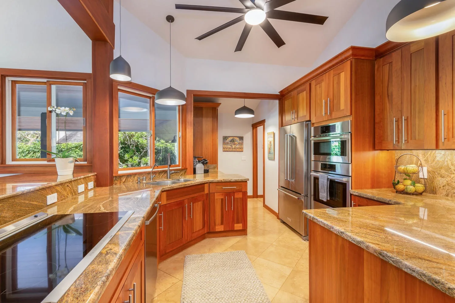 A spacious kitchen with wood cabinets, stone counters, and stainless steel appliances.